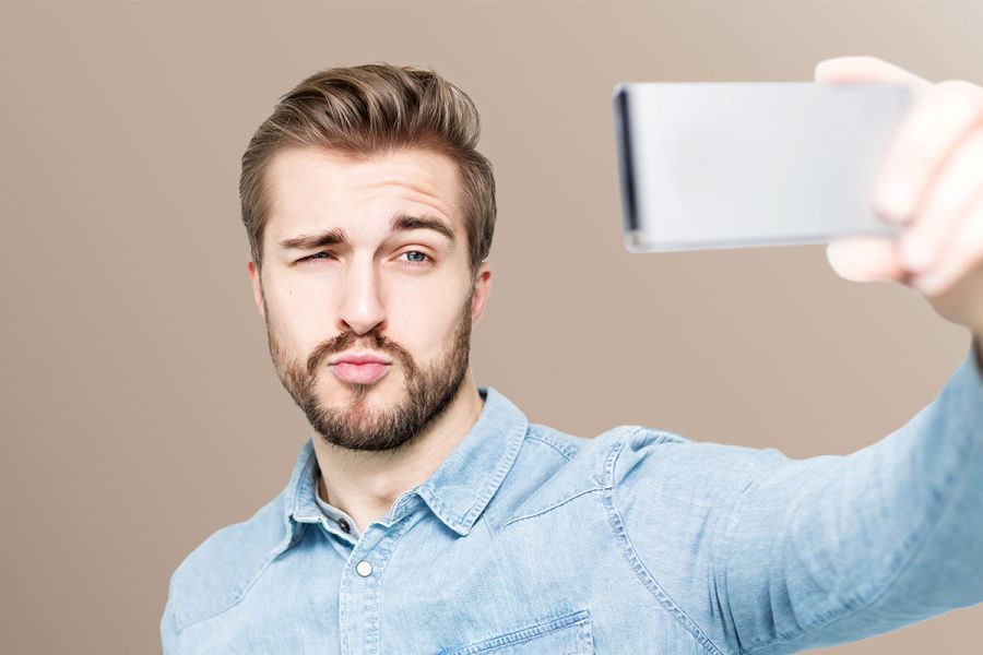 Mann hält Smartphone in der Hand vor sein Gesicht