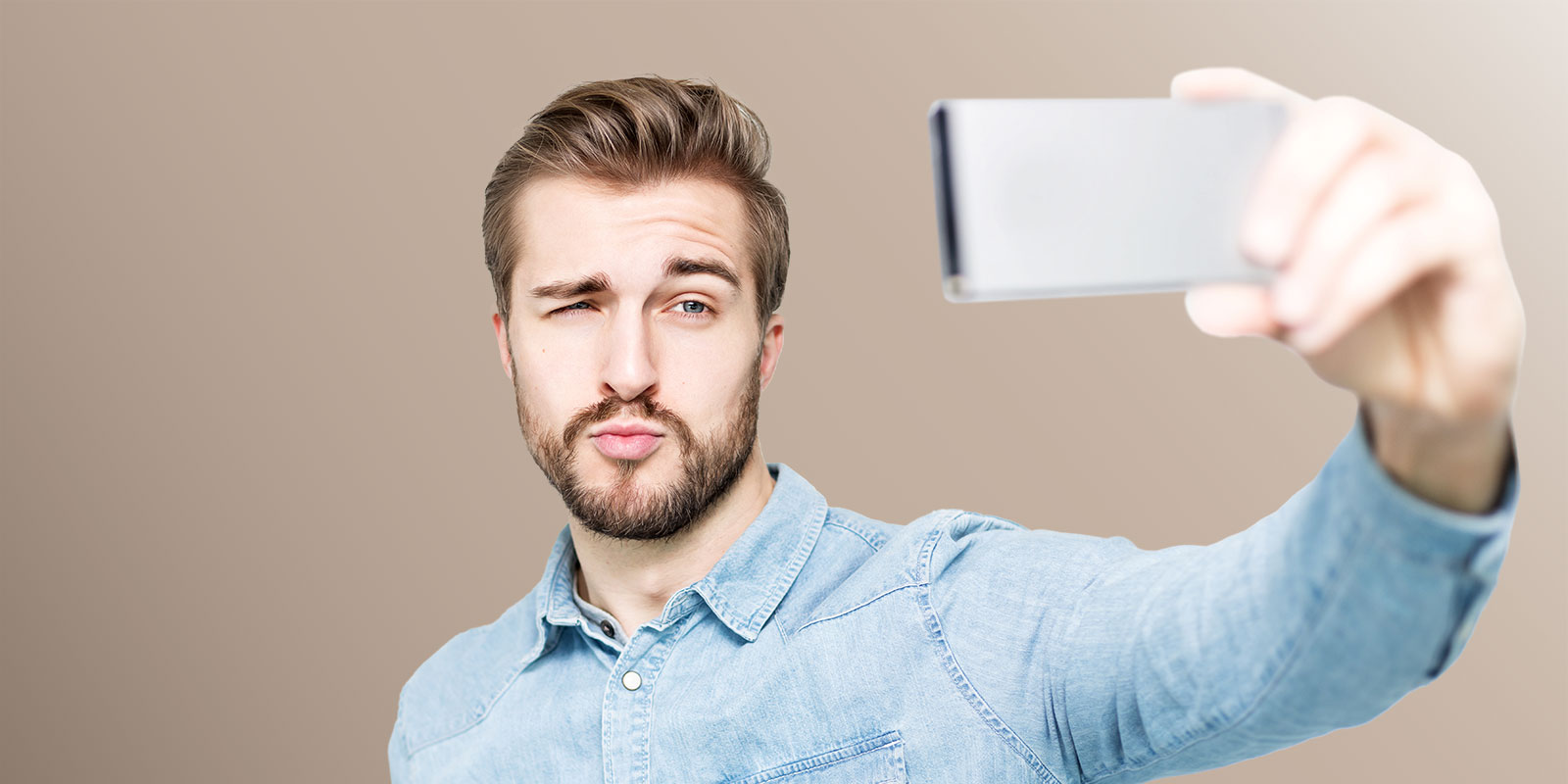 Mann hält Smartphone in der Hand vor sein Gesicht